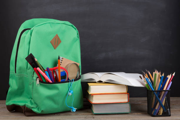 istock Education concept - school backpack with books and other supplies, blackboard background 2148389702