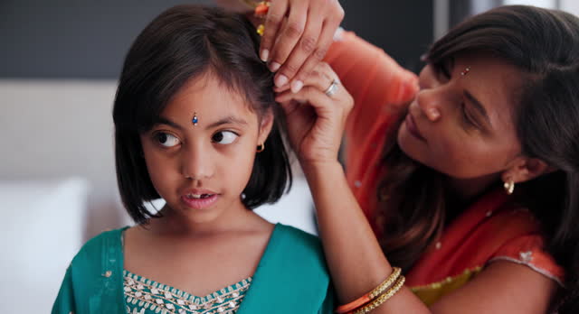 Indian mother brushing child hair in living room of family home with traditional outfit. Love, care and young mom with girl kid getting ready with hairstyle in culture clothes or fashion at house.