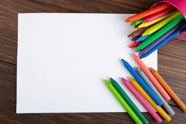 colored crayons and blank page on the wooden table