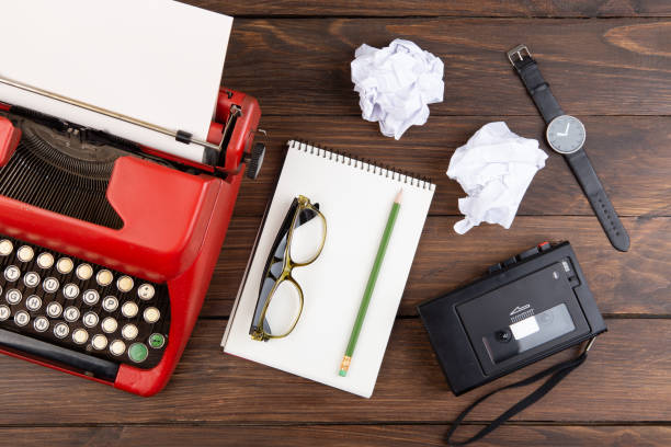 istock Writer or journalist workplace - vintage red typewriter, cassette recorder and notepad on the wooden desk 2148391085
