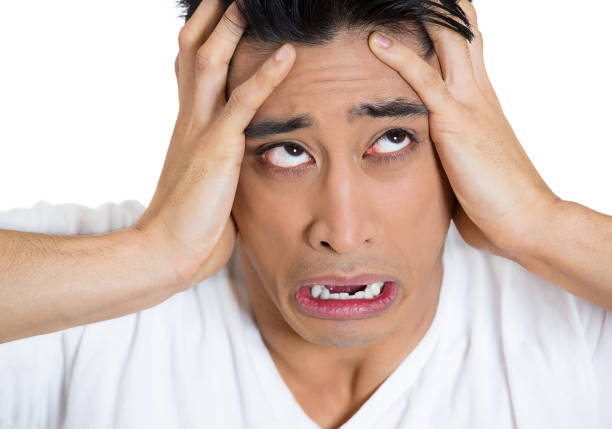 young man feeling stressed suffering from pain screaming desperate with hands on head
