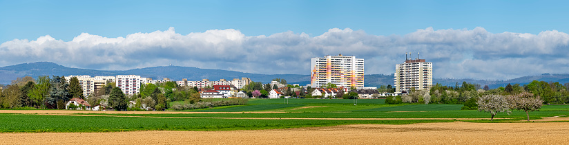 Satellite town on the outskirts of Frankfurt am Main with fields, orchards and the Taunus low mountain range in the background in sunny weather and clear clouds