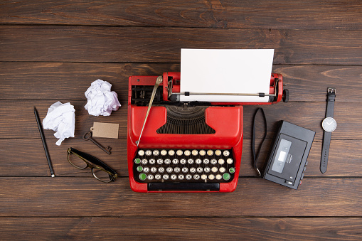 Journalism or blogging concept - vintage typewriter on the wooden desk, top viewvintage typewriter on the table with blank paper on wooden desk - concept for writing, journalism, blogging