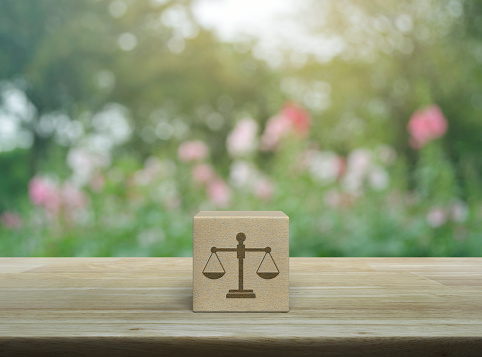 Law icon on wood block cube on wooden table over blur pink flower and tree in park, Business legal service concept