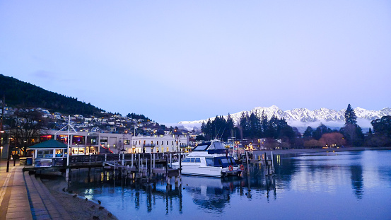 White boats are parked on the foreshore of Queenstown's lake with snow capped mountains in the background
