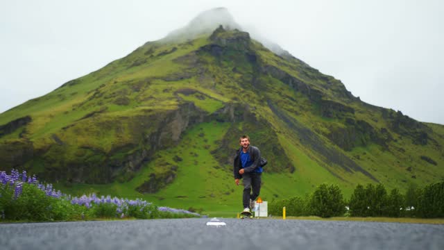 Skater pushes in the road with Icelandic mountains in the background