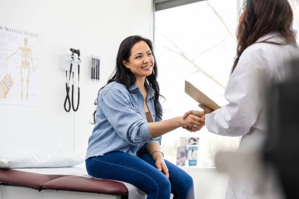 Mid adult female patient shakes hands with her doctor Arriving for her appointment, the unrecognizable female doctor shakes hands with her patient. primary care stock pictures, royalty-free photos & images