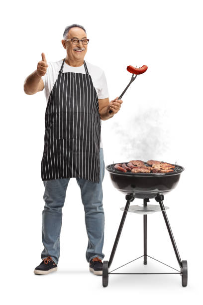 istock Mature man baking meat on a barbecue grill and holding a sausage with a fork 2148393722