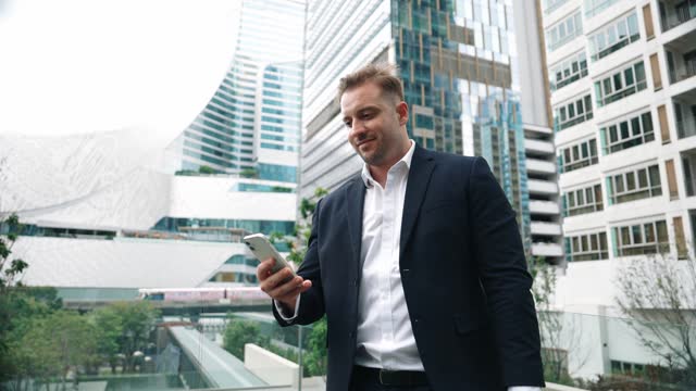 Businessman talking to team by using phone while standing at skyscraper. Urbane.
