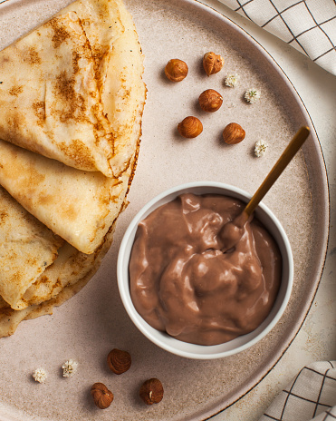 Chocolate mousse with crepes and hazelnuts, a sweet temptation with a golden spoon ready for delight