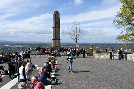 Königswinter, Germany, March 31, 2024 - Tourists sit on the viewing terrace in front of the Landsturm monument on the Drachenfels plateau.