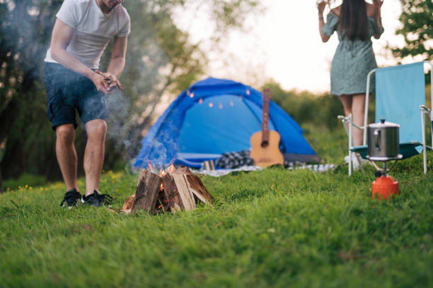 istock Young couple camping, man lighting a fire. 2148395273