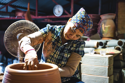 vietnamese woman making jar at pottery wheel in manufacture