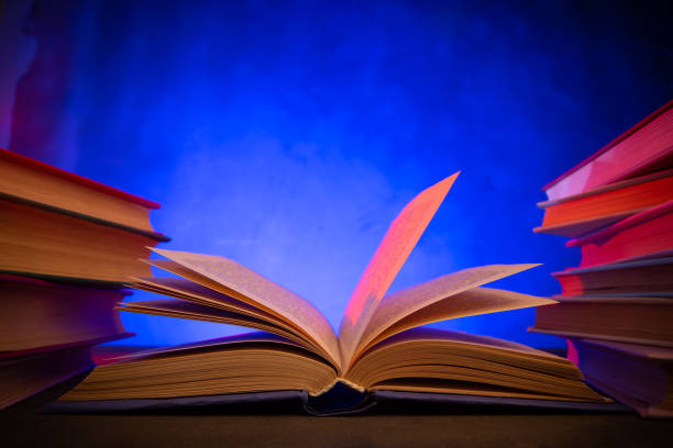 An open book with pages turning on a wooden table set against a green background