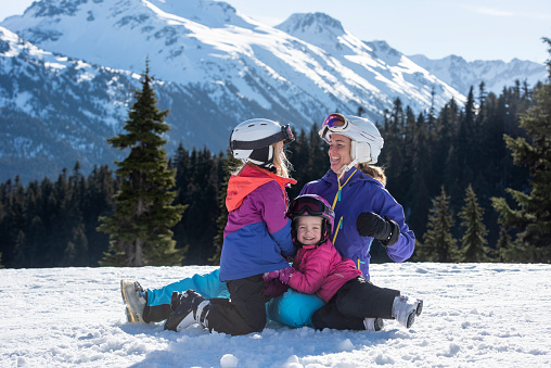 Mother and daughters pause on ski slope at Canadian ski resort on a sunny winter day