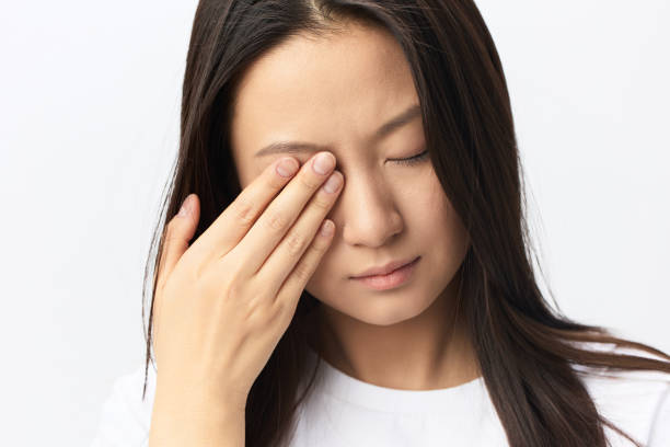 istock Suffering From Strong Pain. Eyesight problem. Tormented suffering tanned beautiful young Asian woman touching eyes posing isolated on white background. Injuries Poor health Illness concept. Cool offer 2148399738
