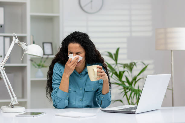 istock Sick woman with cold blowing nose at work desk 2148402123