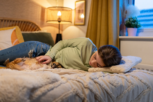 Full shot of a young girl lying on her side on the bed, she is embracing a chihuahua dog. The location is their home located in North East of England in Newcastle Upon Tyne.

Videos are also available for this scenario.