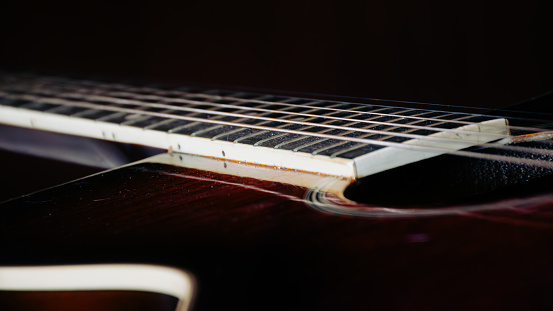 In the midst of a softly lit ambiance, a sleek guitar steals the spotlight. Its curves and details are accentuated in the close-up shot against a backdrop of deep, velvety darkness. The instrument exudes an air of elegance and sophistication, inviting viewers to appreciate its craftsmanship and allure.