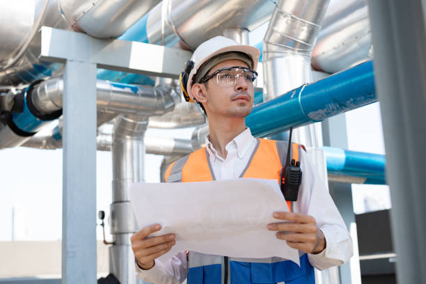 istock Asia male engineer in protective workwear is performing a conducts system check and use walkie talkie with paper work at rooftop building 2148404358