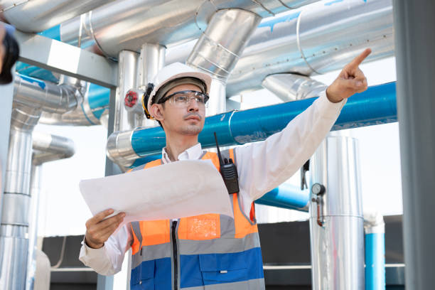 istock Asia male engineer in protective workwear is performing a conducts system check and use walkie talkie with paper work at rooftop building 2148404363