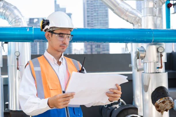 istock Asia male engineer in protective workwear is performing a conducts system check and use walkie talkie with paper work at rooftop building 2148404373