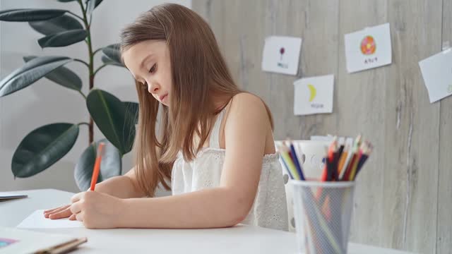 Young girl focused on drawing at the desk at home or school class room