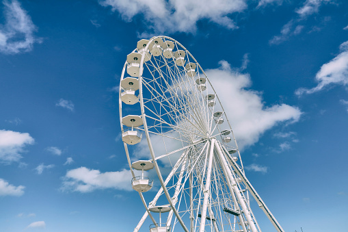White ferris wheel in front of a slightly cloudy blue sky