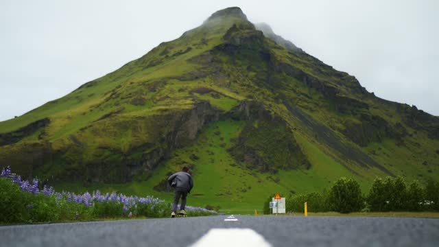 Skateboarder does an epic tre flip in the road in Iceland