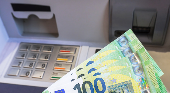Depositing and withdrawing cash euro banknotes from an ATM. Economic and financial concept