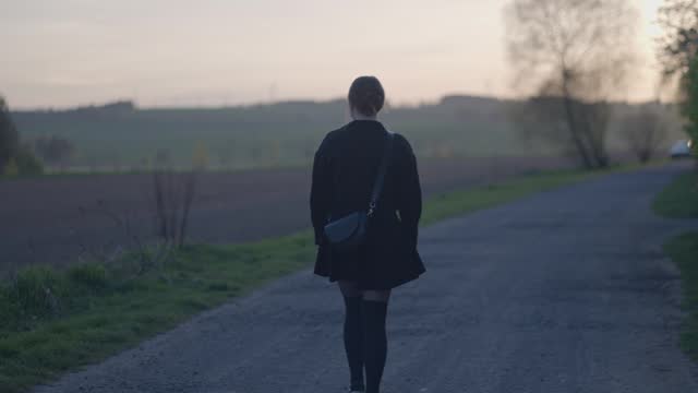 Sad young girl walking alone on the road. The loneliness of young people and the inability to find a relationship culminates in escaping into nature and closing off from society