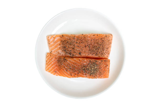 Top view of Raw salmon with pepper in white dish on isolated white background.