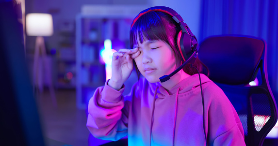 Closeup asian young female teenager gamer feel uncomfortable rubbing eyes while play online internet cyber sport game at home