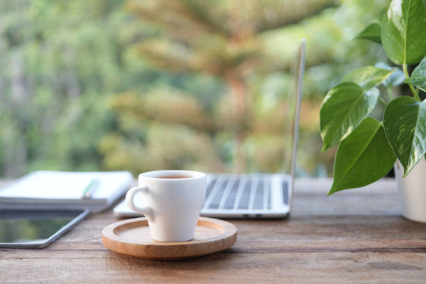 istock Laptop side view and coffee cup with notebooks on white table outdoor 2148409428