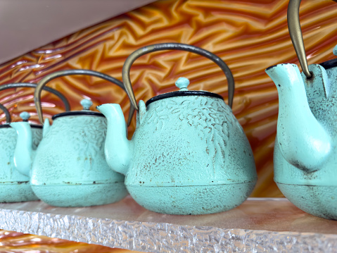 Still life of bronze tea pots side by side on a shelf
