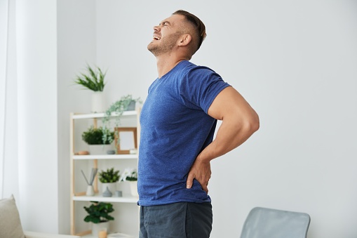 Man back neck and shoulder pain, inflammation of muscles and ligaments rupture during sports, inflammation and injury, in a blue t-shirt at home. High quality photo