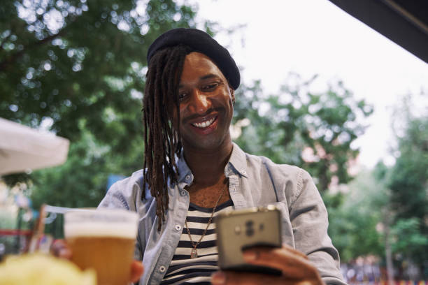 istock black man sitting in a bar drinking beer with his smartphone 2148410910