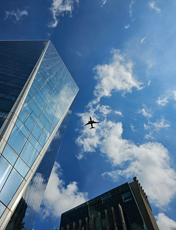 Airplane over the city, with skyscrapers and blue sky with clouds