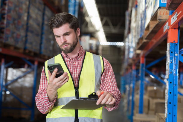 istock Male warehouse worker holding clipboard during working in storage warehouse. Warehouse worker inspecting quality of products on shelf pallet and checking stock inventory 2148411833