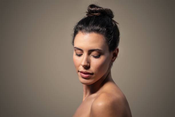 Glowing beauty. Portrait of beautiful young woman with tanned body, well-kept clear skin and nude makeup isolated on white background. Concept of beauty, skin and body care, cosmetology and cosmetics