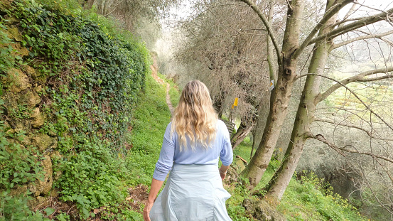 Mature woman hikes through orchard on misty day