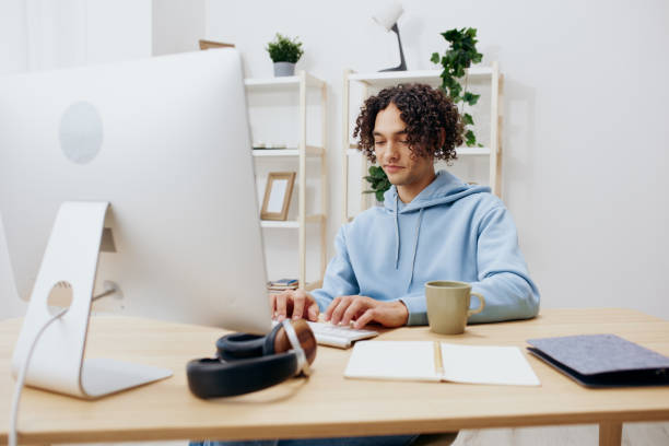 istock guy with curly hair sitting in front of the computer internet online technologies 2148414896
