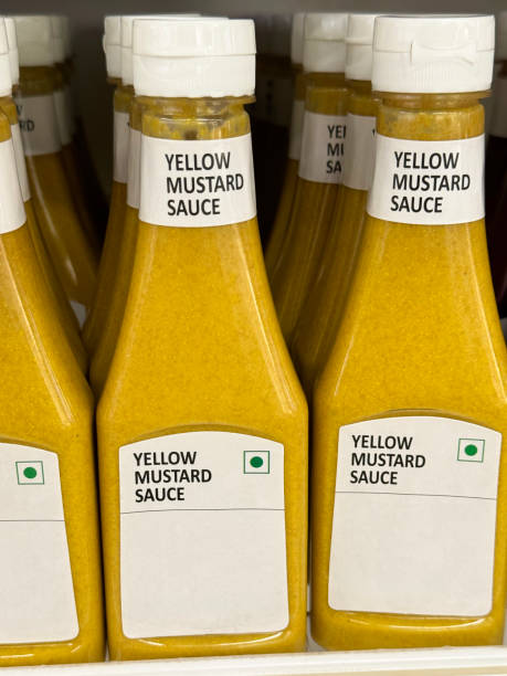 istock Full frame image of retail shelf containing rows of labelled plastic bottles full of condiments, capped bottles of yellow, mustard sauce, focus on foreground 2148414920