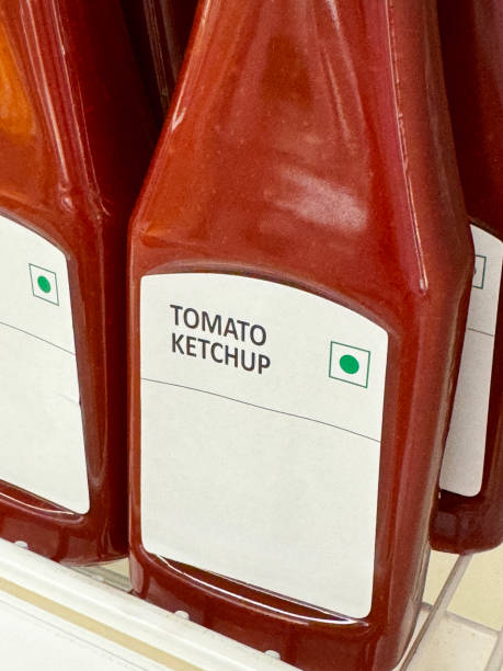 istock Full frame image of retail shelf containing rows of labelled plastic bottles full of condiments, capped bottles of red, tomato ketchup, focus on foreground 2148414929