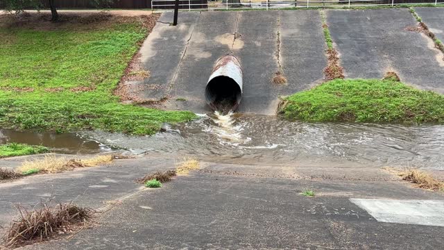 Water flowing from large pipe into drainage ditch