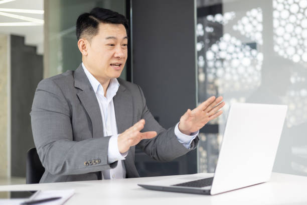 istock Asian businessman in office making video call on laptop 2148415659