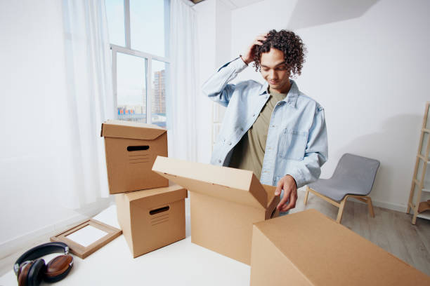 istock A young man cardboard boxes in the room unpacking headphones sorting things out 2148415707