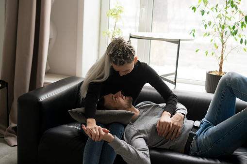 Couple in Love Relaxing Together on a Sofa in casual clothes in a Cozy Living Room at home