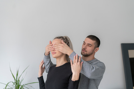 man and woman covering eyes from behind and making a surprise