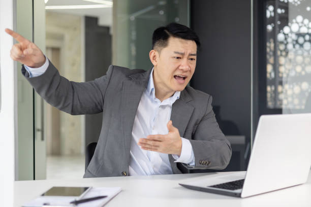 istock Angry Asian businessman in video call at office 2148416656
